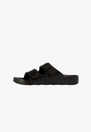 Sandalia negra tipo slide con punta abierta, dos correas ajustables con hebillas y suela texturizada, vista lateral sobre fondo blanco.