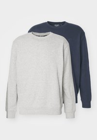To sweatshirts med rund hals stablet; en grå og en marineblå. Begge har ribbede manchetter og et lille logo på brystet. Blødt stof. 