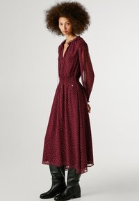 Burgundijas midi kleita ar punktiem, caurspīdīga auduma, smockēta josta, garas piedurknes un ar kakla saiti, apvienota ar ceļgala augstuma melnām botām.