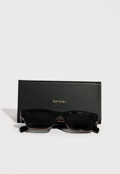 Gafas de sol rectangulares negras con un acabado brillante, que presentan un detalle de carey en los bordes. Vienen con un estuche de cuero negro con letras doradas.