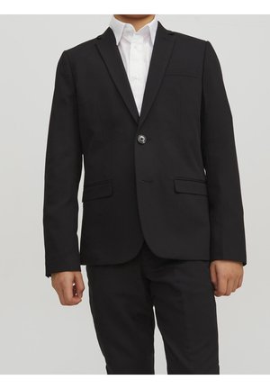 Blazer negro con un solo botón, dos bolsillos frontales y solapa con muesca, combinado con una camisa blanca. Tejido suave, corte entallado.