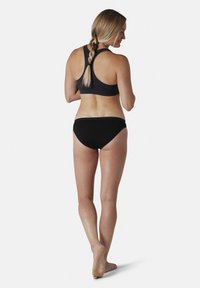 Sort sports-bh med racerback-design og matchende sorte bikini-bukser. Glat stof, minimale sømme og neutral farvepalette.