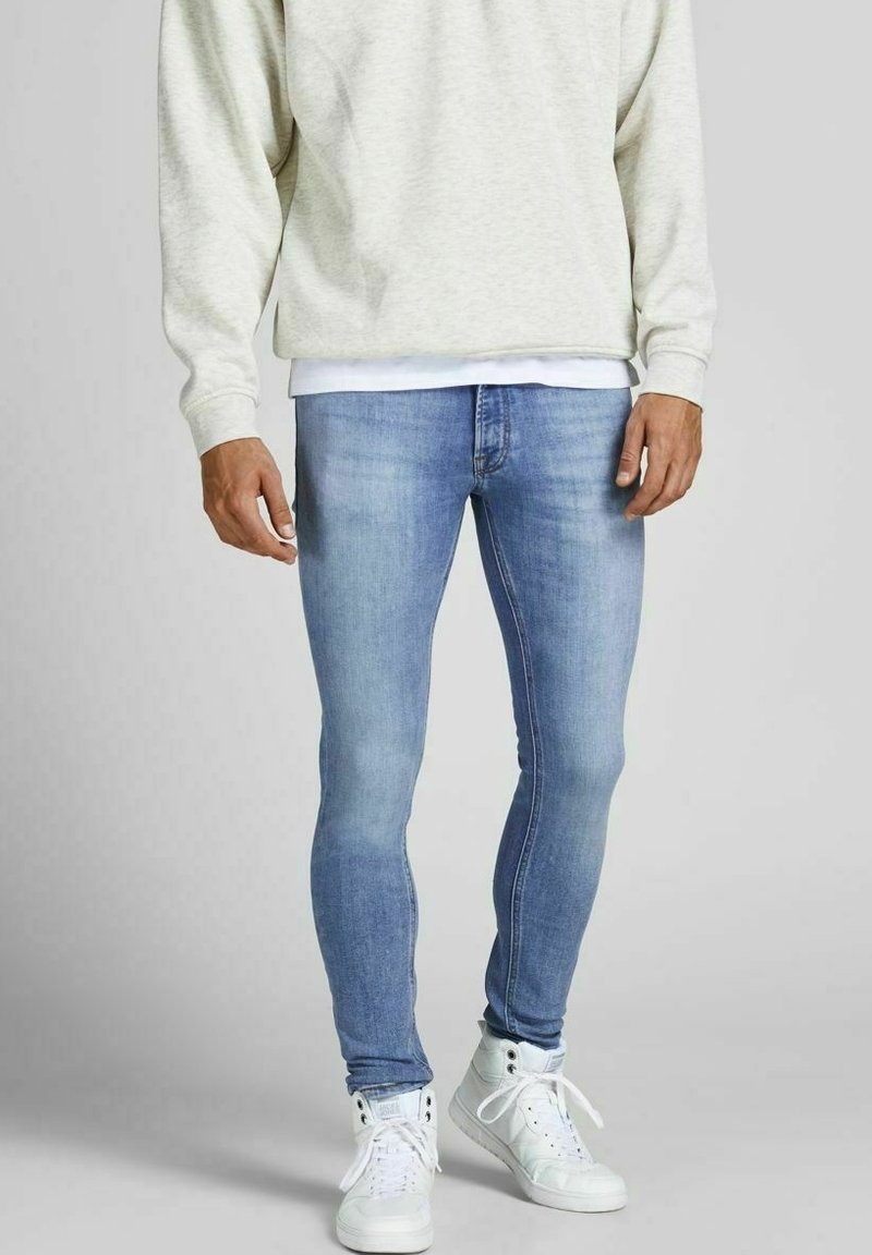 Light blue slim-fit jeans made of denim, featuring a classic five-pocket design, paired with a light gray sweatshirt and white sneakers.