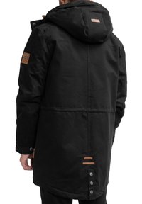 Sort parka-jakke med hætte, med en struktureret stof, brune læderdetaljer, sidelommer og knapdetaljer ved kanten.