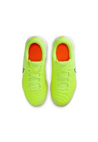 Zapatillas deportivas verde lima con superficie texturizada, suelas blancas, logo negro y plantillas de color naranja vibrante. Incluyen cordones y diseño de soporte.