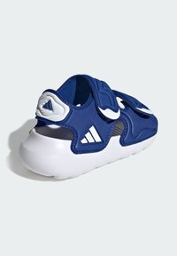 Granatowa sandał z paskami na rzepy, białe detale i teksturowana podeszwa. Posiada wycięcia zapewniające przewiewność oraz ergonomiczną konstrukcję.