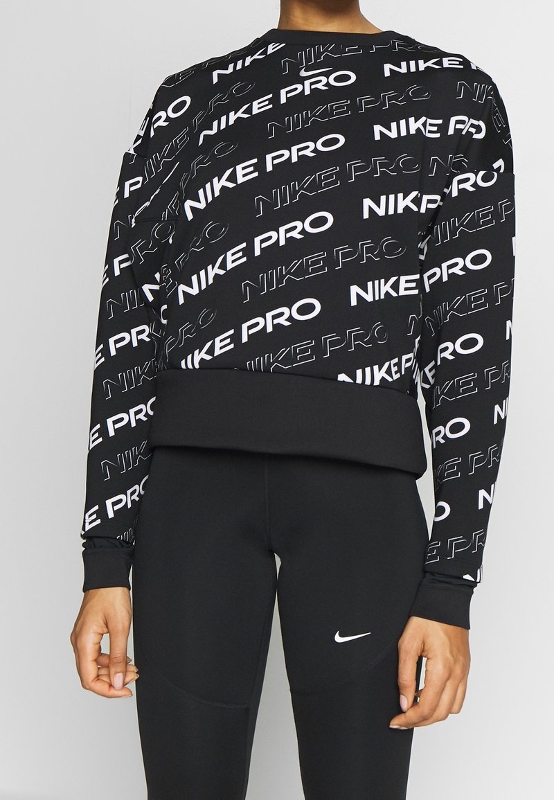 Felpa nera con testo bianco "NIKE PRO" in un motivo ripetuto. Maniche lunghe e orlo aderente. Il materiale sembra liscio e elasticizzato.