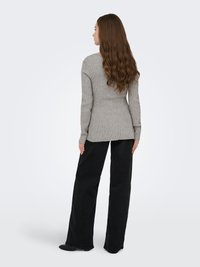 Pull gris à côtes avec manches longues, ourlet légèrement arrondi, assorti à un pantalon large noir et des chaussures plates noires, vu de dos.