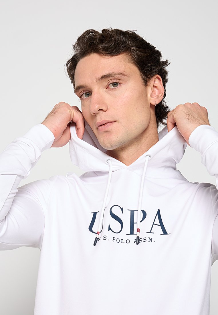 Sudadera blanca con bolsillo tipo canguro, capucha con cordón y logo "USPA" en azul marino. Tejido suave; mangas ajustadas; diseño minimalista.
