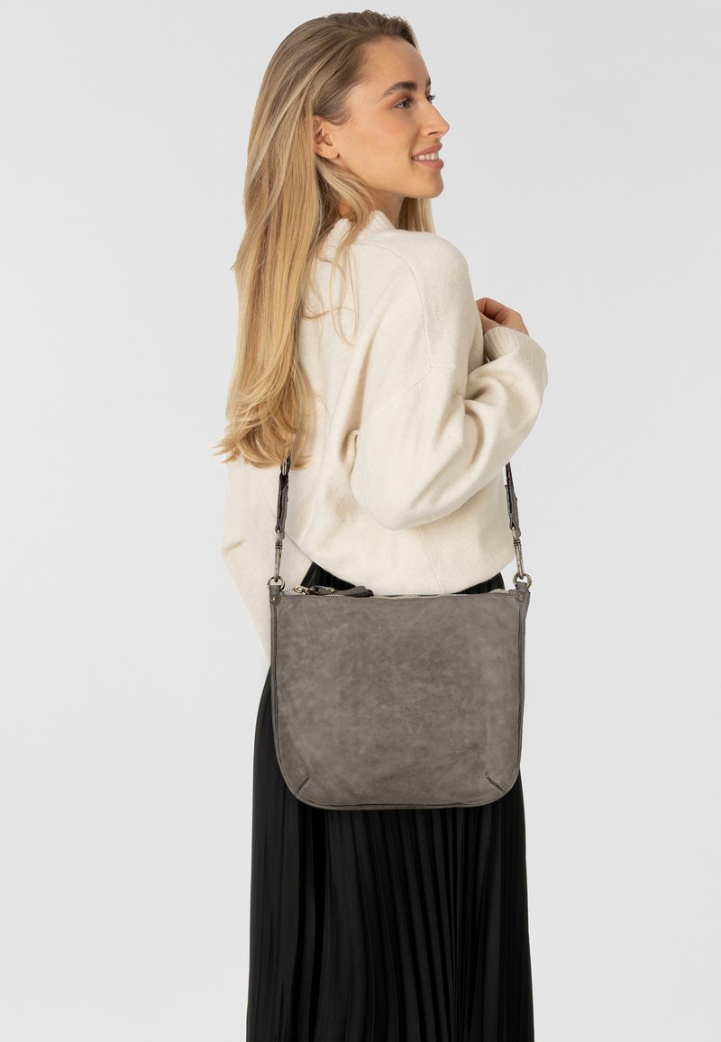 Borsa a spalla in pelle grigia con una texture liscia, chiusura con zip e tracolla regolabile, caratterizzata da un design minimalista e angoli arrotondati.