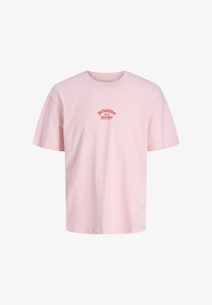 Šviesiai rožinė medvilninė marškinėliai su trumpomis rankovėmis, apykaklė apvali, ir raudonu išsiuvinėtu tekstu, skaitančiu "PERDIDO en el PARAISO" ant krūtinės.