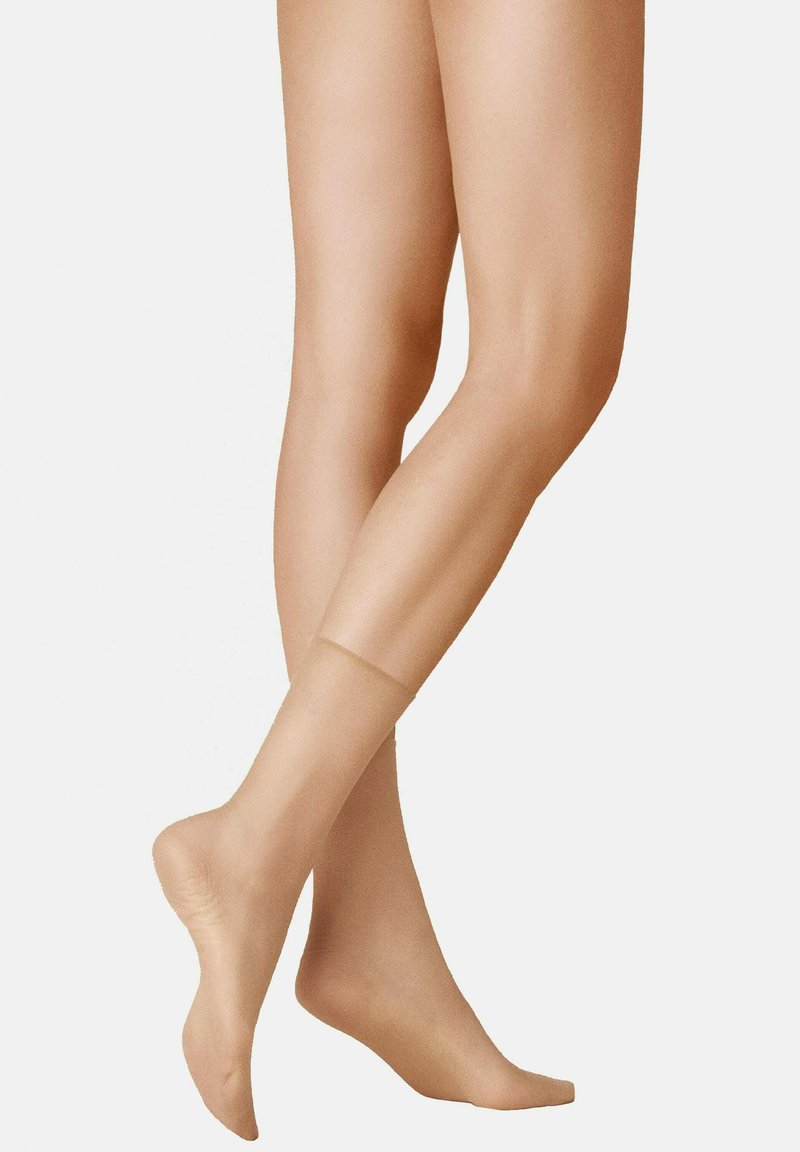 Beige, transparente Strumpfhosen mit glatter Textur, ausgestattet mit einer verstärkten Spitze und einem dezenten Glanz, die eng an den Beinen anliegen.