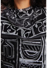 Tissu noir avec des motifs abstraits blancs. Le matériau a une texture lisse avec un col bénitier et des détails de conception superposés.