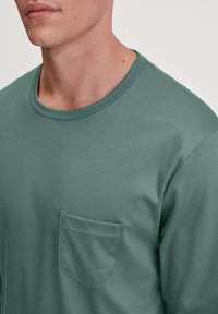 Groene lange mouwen T-shirt van zacht katoen, met een ronde halslijn en een borstzak. Soepele textuur, minimalistisch ontwerp.