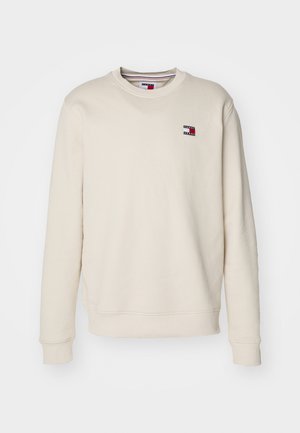 Beiger Sweatshirt mit langen Ärmeln und ribbed Bündchen. Mit einem kleinen Logo in Rot und Blau. Weicher Stoff mit Rundhalsausschnitt.