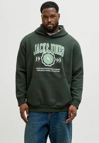 Sudadera de color verde oscuro con un gráfico frontal que presenta "JACK&JONES 1990" en blanco y verde. El material parece suave; incluye un bolsillo tipo canguro.
