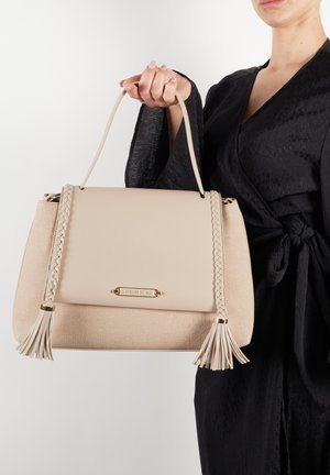 Borsa a tracolla beige con finitura testurizzata, accentuata da trecce, hardware dorato e frange decorative. Design strutturato con manico superiore.