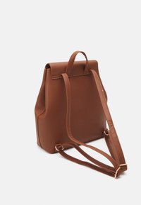 Hnědý batoh z umělé kůže se strukturovaným designem, horním držadlem a nastavitelnými ramenními popruhy. Disponuje hladkým povrchem a minimálním kovovým příslušenstvím.