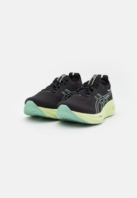 Zapatillas deportivas negras con un upper de malla, detalles en verde y una suela verde claro con un diseño de textura. Diseño ligero y ergonómico.