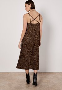 Sukienka midi w leopardzi wzór z krzyżującymi się plecami, wykonana z miękkiej tkaniny. Posiada swobodny krój i świetnie komponuje się z czarnymi botkami za kostkę.