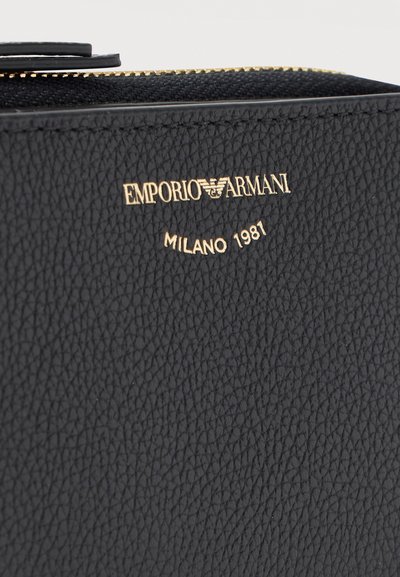 Μαύρο πορτοφόλι από δερματίνη με ανάγλυφο χρυσό λογότυπο Emporio Armani και το κείμενο "Milano 1981" κάτω από ένα χρυσό φερμουάρ.