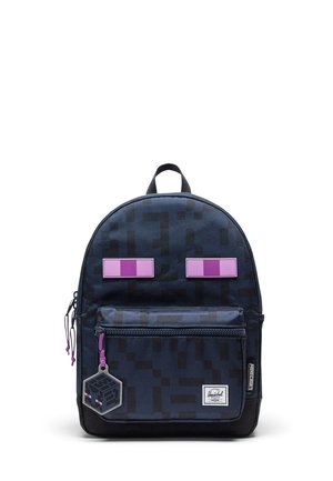 Sac à dos bleu foncé à motif pixélisé, deux patchs rectangulaires violets ressemblant à des yeux, poche avant et porte-clés hexagonal attaché.