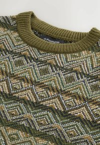 Olívazöld kötött pulóver nyaka, geometrikus mintázattal zöld, barna, fehér és fekete árnyalatokban, bordás gallérral.