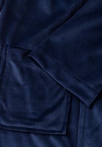 Laivastonsinistä corduroykangasta, jossa on pystysuora ribbineulos, suorakaiteen muotoinen tasku ja taitettu hiharesoritasku.