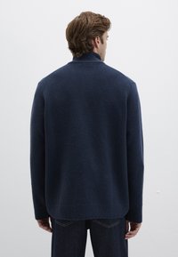 Navy blue, lightweight wool blend sweater with a high collar and dropped shoulders, featuring a soft texture and straight hemline.