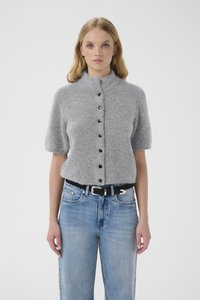 Pulover gri cu mâneci scurte dintr-o textură moale, cu guler înalt și detalii cu nasturi negri, asortat cu blugi albastru deschis, cu talie înaltă.