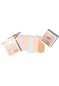 Palette de correction des couleurs comprenant six teintes crème dans un étui blanc. Les couleurs incluent lavande, menthe, pêche et beige. Couvercle transparent et design minimaliste.