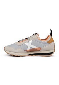 Zapatillas gris claro con un upper de ante texturizado y sintético. Presenta una franja diagonal blanca, acentos naranjas y una suela negra.