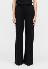 Μαύρο παντελόνι με φαρδιά πόδια από απαλό ύφασμα, με ελαστική μέση και μικρή διακριτική λογότυπη λεπτομέρεια. Λείο ύφασμα και σχεδίαση πλήρους μήκους.