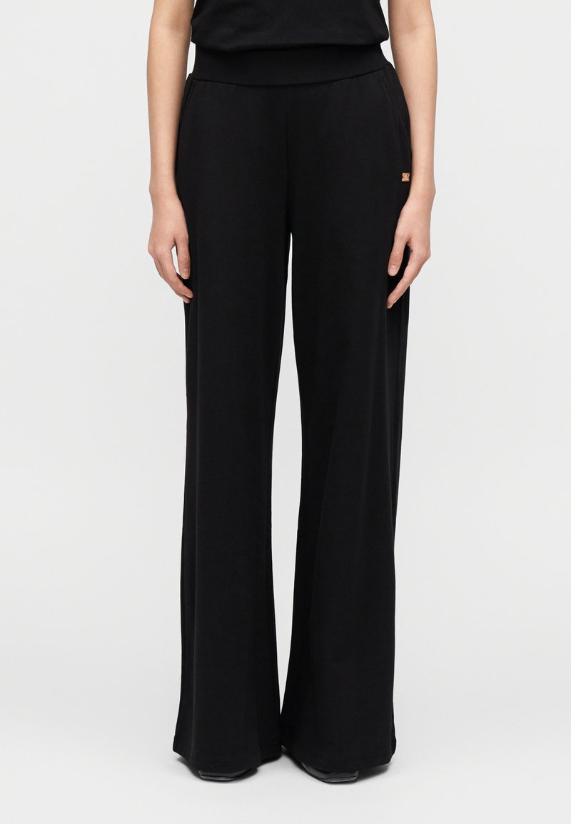 Μαύρο παντελόνι με φαρδιά πόδια από απαλό ύφασμα, με ελαστική μέση και μικρή διακριτική λογότυπη λεπτομέρεια. Λείο ύφασμα και σχεδίαση πλήρους μήκους.