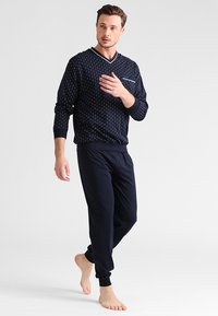 Conjunto de lounge en color navy que incluye una blusa de manga larga con un patrón y escote en V, así como pantalones ajustados a juego, ambos elaborados en una tela suave.