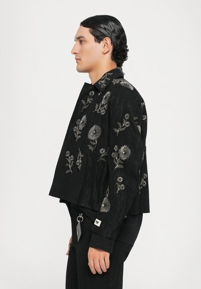 Schwarze, kurze Jacke aus strukturiertem Stoff mit aufwendiger silberner Blumenstickerei. Enthält einen Kragen und eine Seitenpocket.