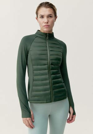 Giacca unisex verde con design aderente, presenta pannelli frontali trapuntati, maniche lunghe, colletto alto e fori per il pollice alla fine delle maniche.