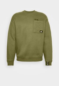Sweat-shirt vert olive avec poche poitrine matelassée, patch logo noir, poignets côtelés et coordonnées imprimées au-dessus de la poche.