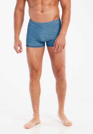 Blue patterned swim shorts with a diamond design, featuring an elastic waistband and a fitted cut, made from stretchable material.