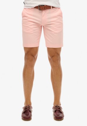 Rosa Shorts aus leichtem Material, slim fit, mit umgeschlagenem Saum, kombiniert mit burgunderfarbenen Bootsschuhen und einem braunen Gürtel.