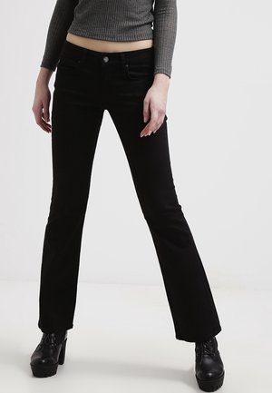Black flared jeans made of denim, featuring a front button closure and belt loops, paired with chunky black platform boots.