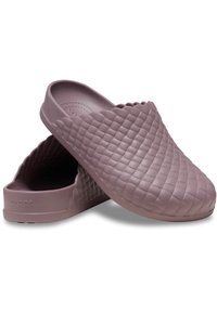 Lila Gummischuhe verfügen über ein strukturiertes, gestepptes Muster und gewellte Kanten. Das Schuhwerk hat ein offenes Rückendesign und ein glattes Inneres.