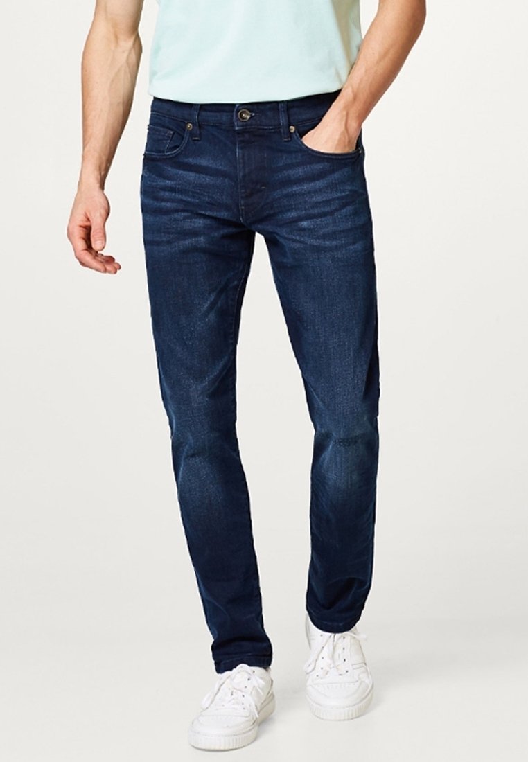 Mörkblå jeans i denim, med slim fit, femfickorsdesign och subtila blekningar. Matchas med vita sneakers.