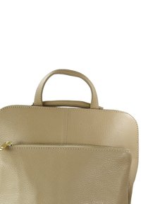 Sac en cuir beige avec une poignée supérieure, présentant une surface texturée, une poche avant zippée et des détails de couture subtils.
