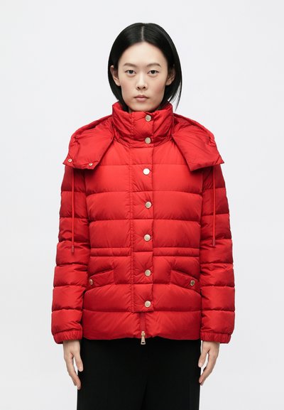 Veste matelassée rouge avec un col montant, des boutons-pression, des poches latérales et une capuche amovible. Texture lisse avec une finition brillante.