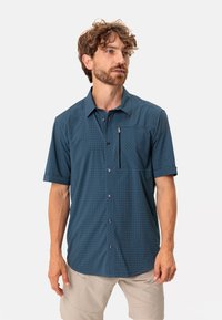 Camisa de botones de manga corta en azul oscuro con patrón de cuadrícula, que cuenta con un bolsillo con cremallera, botones en contraste y un corte relajado.