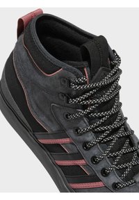 Zapatillas altas en negro y gris con parte superior de ante y textil, que cuentan con detalles en negro y burdeos, cordones gruesos y una suela texturizada.