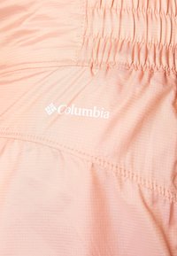 Svetle růžová bunda Columbia s texturovaným povrchem, staženými elastickými detaily a bílým logem na boku.