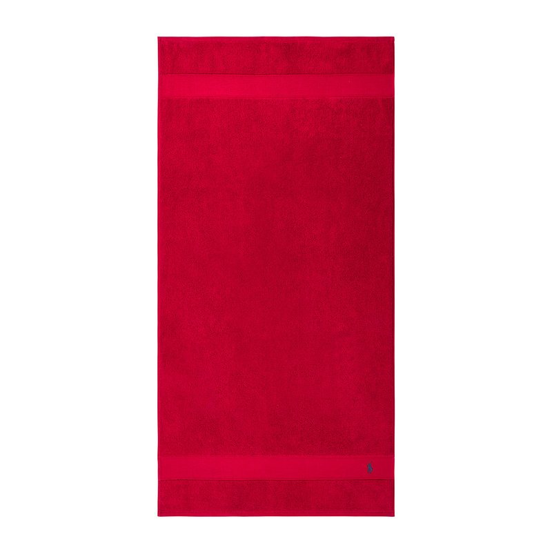 Κόκκινη βαμβακερή πετσέτα με λείο υφή, jednolit χρώμ α και λωρίδα σε αντίθεση κοντά στο κάτω μέρος με μικρό κεντημένο λογότυπο.