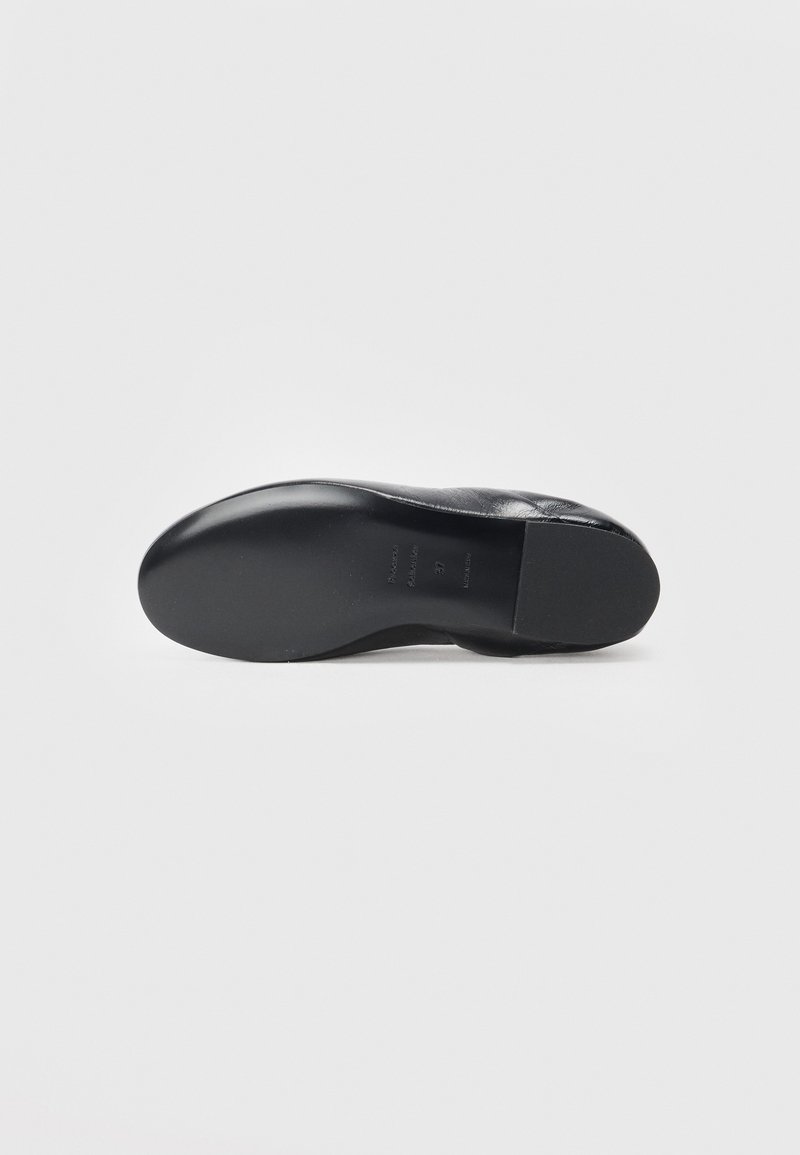 Black leather shoe sole with a smooth, curved shape, featuring a textured surface and flat heel. Interior details are not visible.